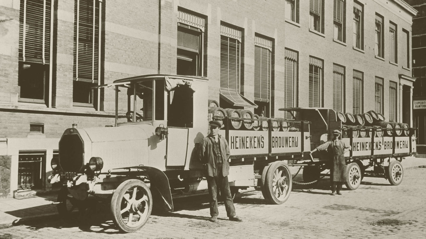 Vintage Heineken trucks and workers outside brewery in Amsterdam, showing the brand’s historic roots